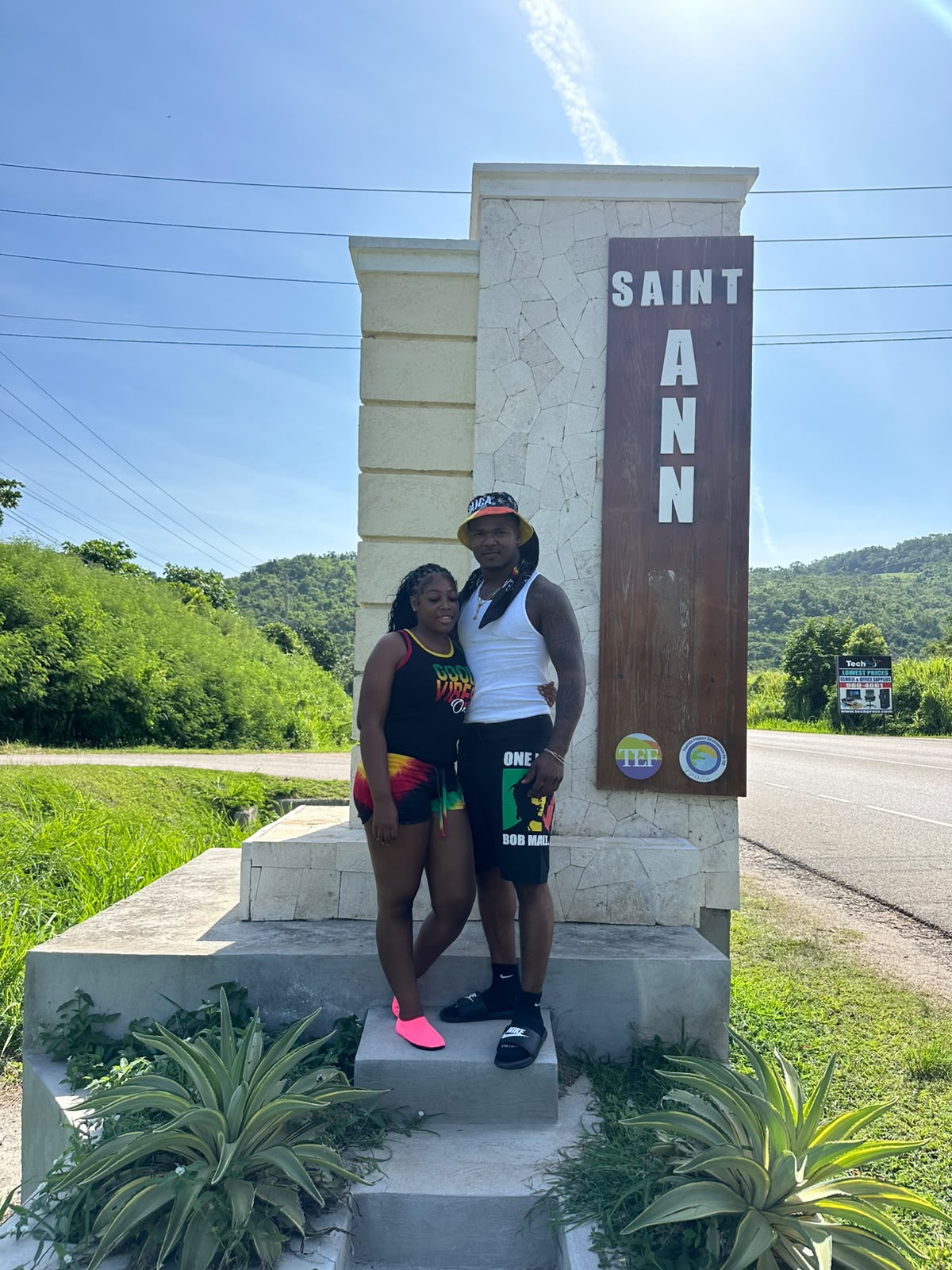 D-Xaymaca guests posing beside the Saint Ann sign with green hills behind them